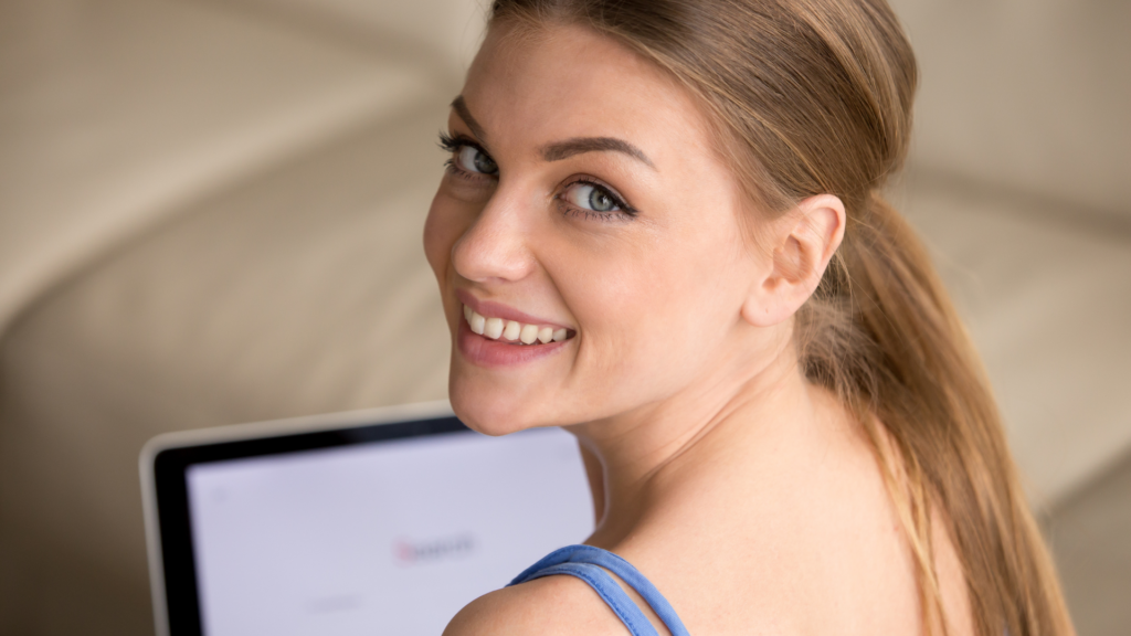 A smiling patient behind her computer after a teledermatology session.